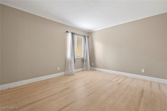 spare room with ornamental molding, wood finished floors, and baseboards