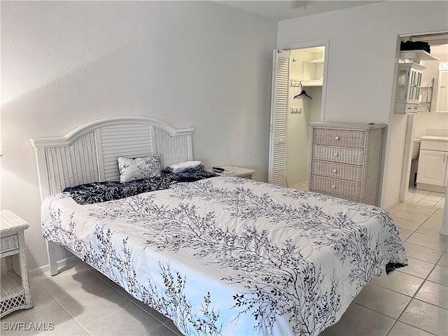 bedroom with ensuite bathroom and light tile patterned floors