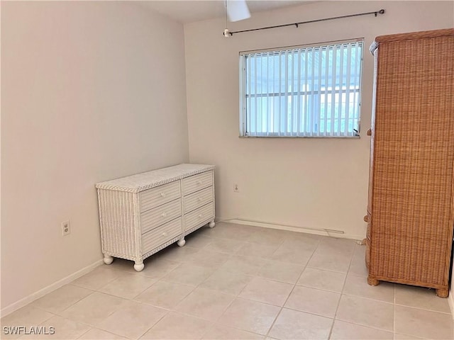 unfurnished bedroom with light tile patterned flooring and baseboards