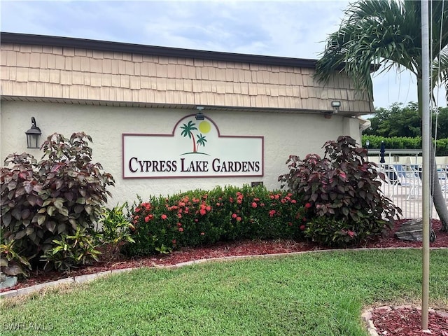 community / neighborhood sign with a lawn and fence