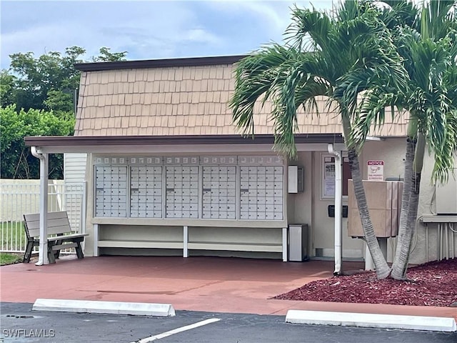 view of community with uncovered parking, fence, and mail area