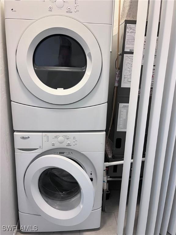 laundry room featuring stacked washer and clothes dryer, light tile patterned flooring, and laundry area