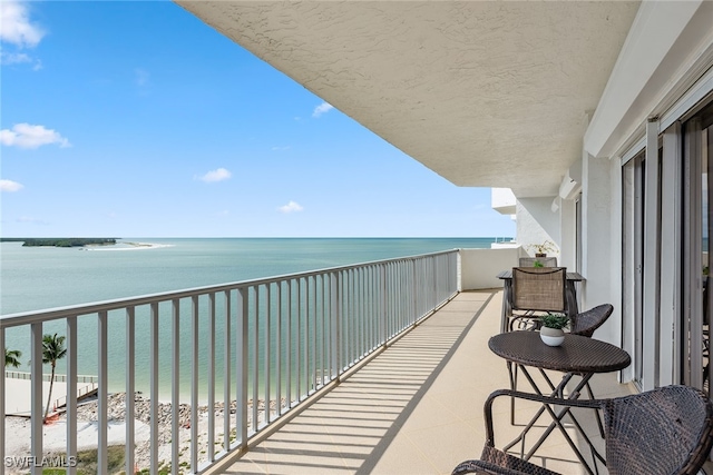 balcony featuring a view of the beach and a water view