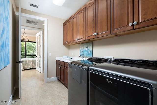 laundry area featuring washer and dryer, sink, cabinets, and a chandelier