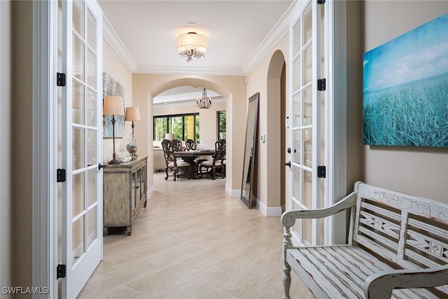 hallway featuring ornamental molding, a chandelier, and french doors