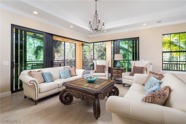 living room featuring an inviting chandelier, ornamental molding, and a raised ceiling