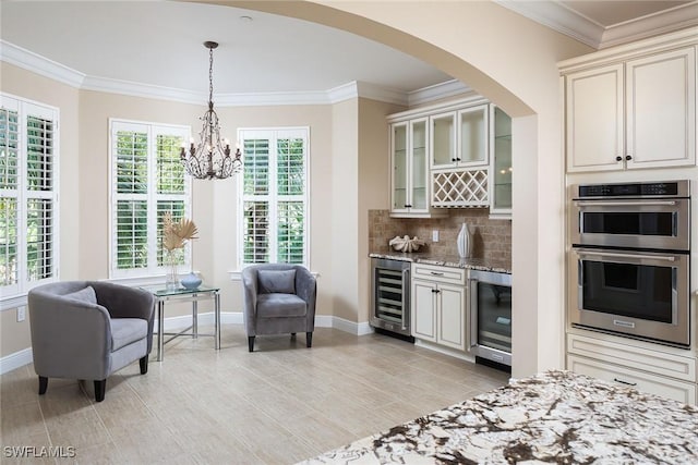 kitchen with wine cooler, double oven, crown molding, and light stone counters