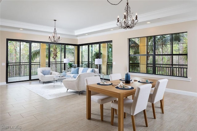 dining space with a raised ceiling, a notable chandelier, and ornamental molding