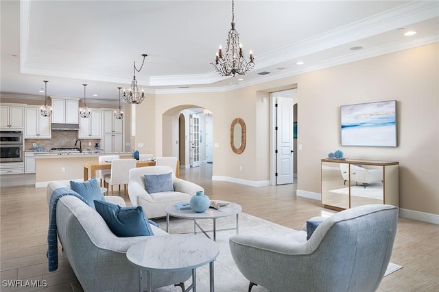 living room featuring light hardwood / wood-style floors, a tray ceiling, and ornamental molding