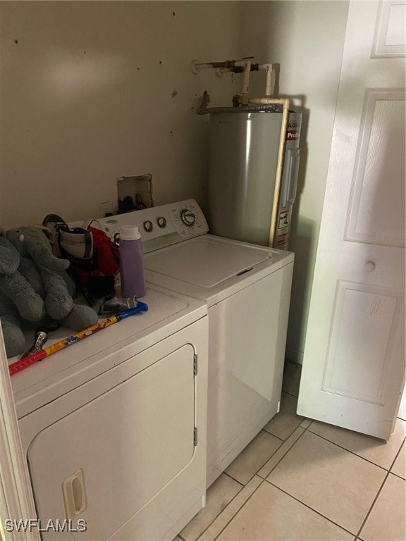 laundry room featuring water heater, light tile patterned flooring, and separate washer and dryer