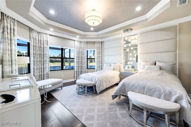 bedroom with hardwood / wood-style flooring, a raised ceiling, ornamental molding, and a water view