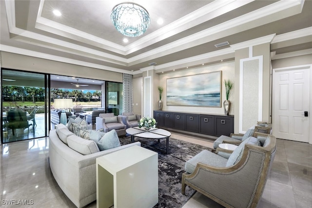 living room with a tray ceiling, crown molding, and a chandelier