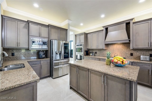 kitchen featuring appliances with stainless steel finishes, backsplash, custom range hood, sink, and a kitchen island