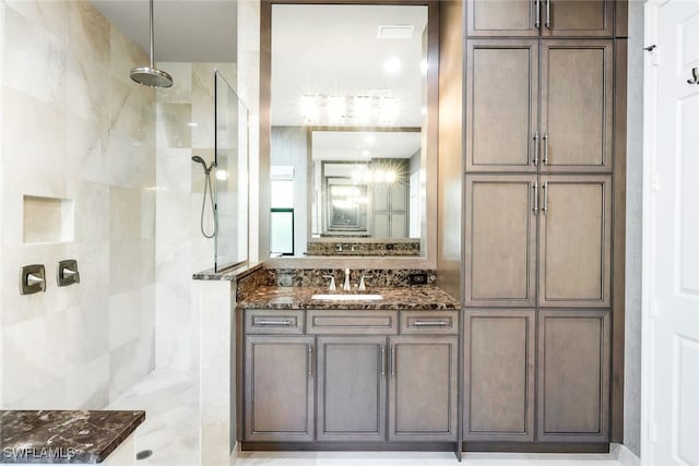 bathroom featuring tiled shower and vanity