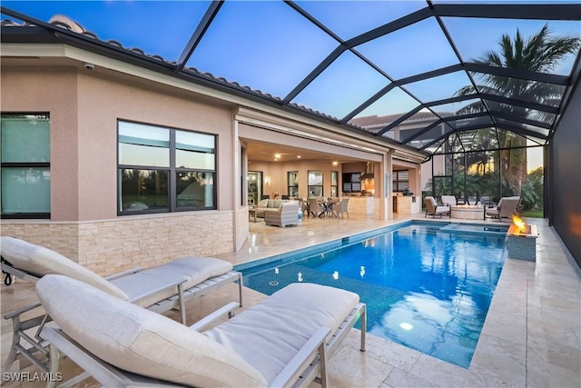 pool at dusk featuring outdoor lounge area, a patio, and glass enclosure