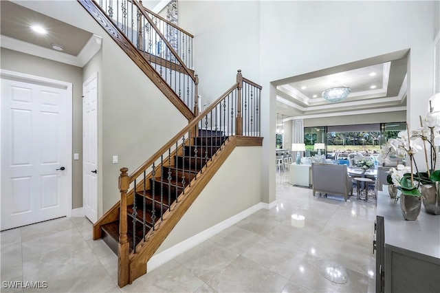 stairs featuring ornamental molding, a tray ceiling, and an inviting chandelier