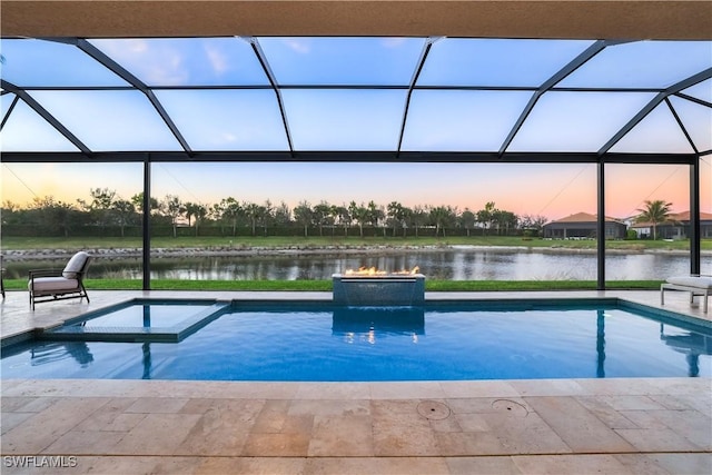 pool at dusk with a lanai, an in ground hot tub, a water view, and a patio