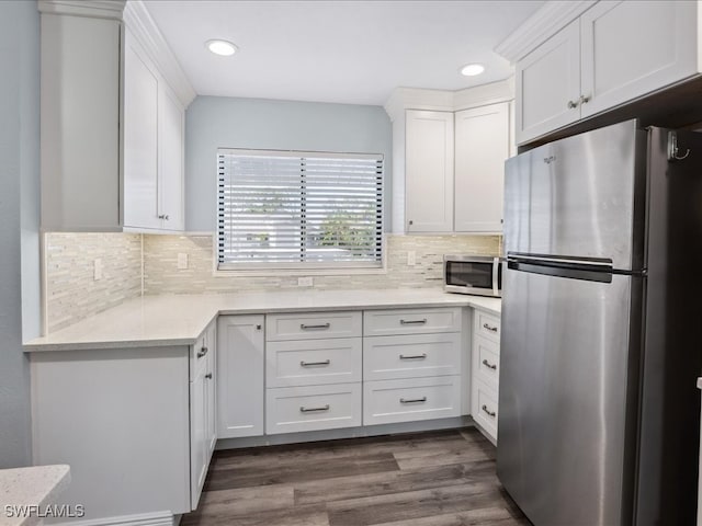 kitchen with dark hardwood / wood-style floors, stainless steel appliances, backsplash, and white cabinets