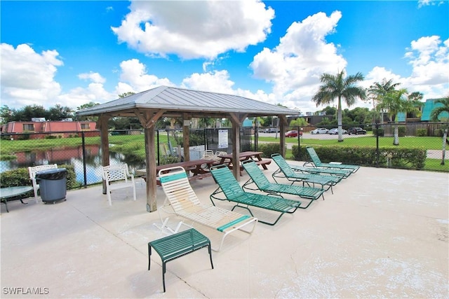 view of community featuring a gazebo, fence, a patio area, and a water view