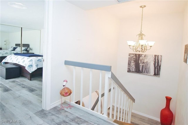 staircase featuring a chandelier, wood finished floors, and baseboards
