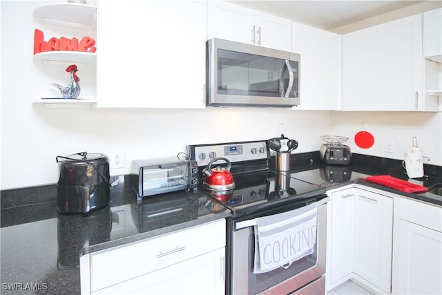 kitchen featuring stainless steel appliances, open shelves, white cabinets, and dark stone countertops