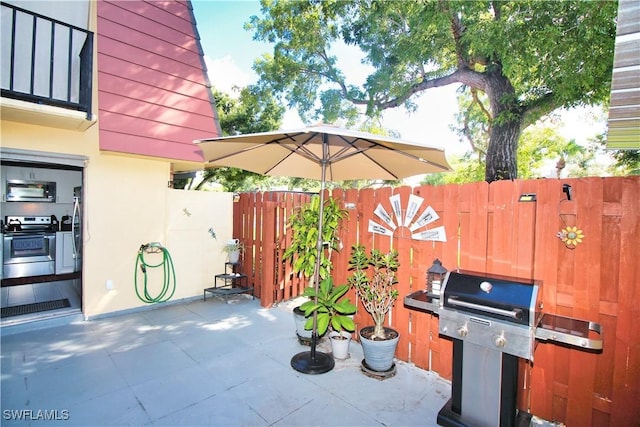view of patio featuring fence and a grill