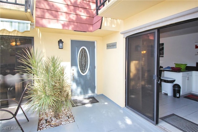 view of exterior entry featuring stucco siding and a balcony