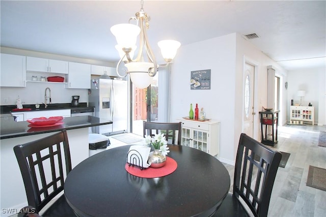 dining room with plenty of natural light, a chandelier, light wood finished floors, and baseboards
