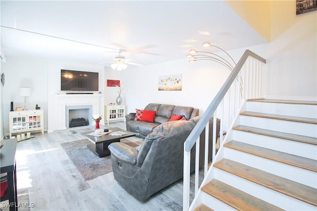living room featuring wood finished floors, a ceiling fan, stairway, and a fireplace