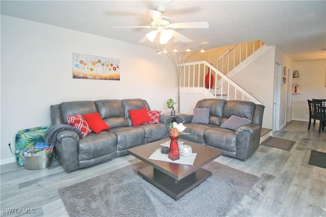 living area with wood finished floors, stairs, a ceiling fan, and baseboards