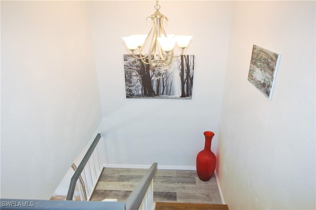 stairway featuring a chandelier, wood finished floors, and baseboards