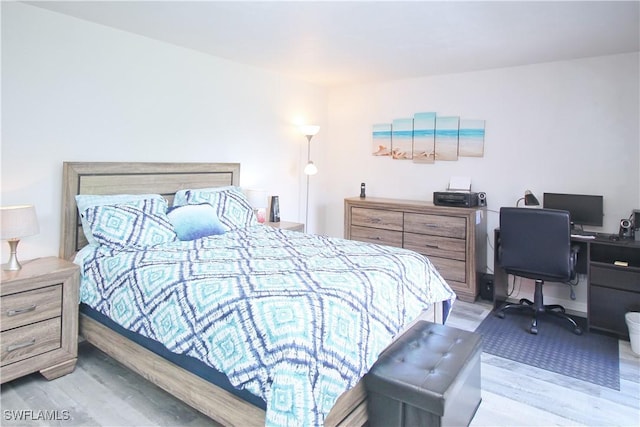 bedroom featuring wood finished floors and an office area