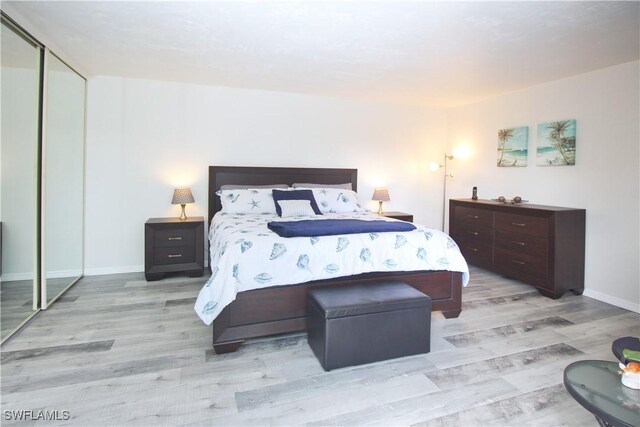 bedroom with wood finished floors, baseboards, and a closet