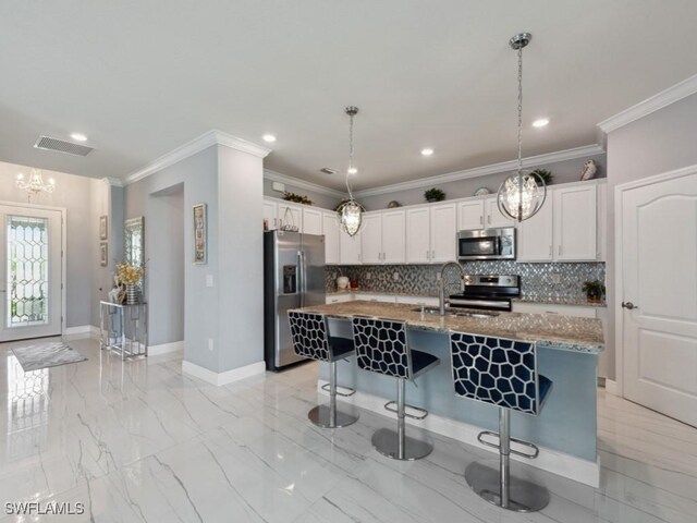 kitchen with sink, an island with sink, a kitchen bar, white cabinets, and appliances with stainless steel finishes