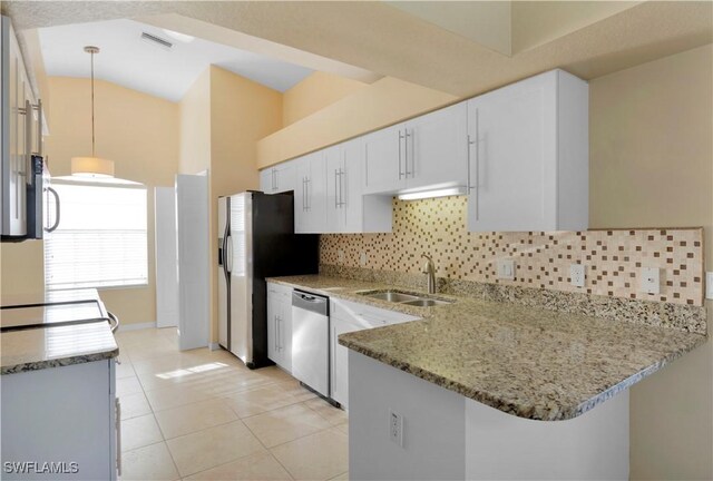 kitchen with appliances with stainless steel finishes, white cabinetry, light stone counters, decorative light fixtures, and kitchen peninsula