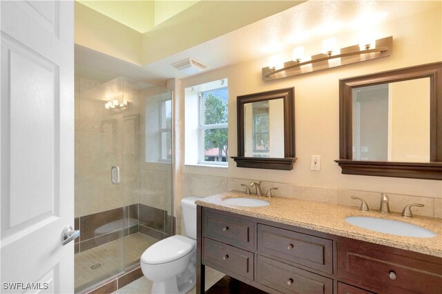 bathroom with vanity, toilet, and a shower with door