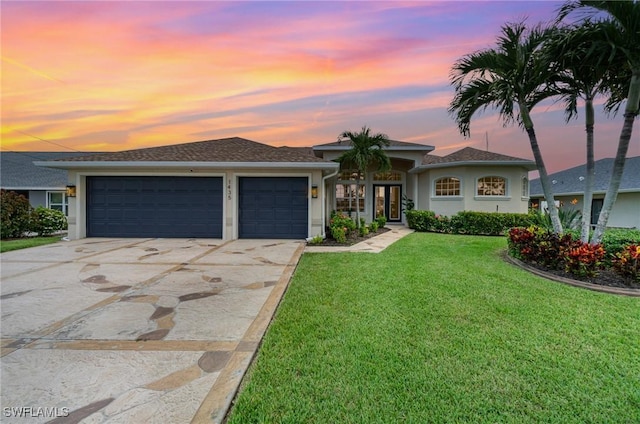 view of front of home featuring a garage, driveway, a front lawn, and stucco siding