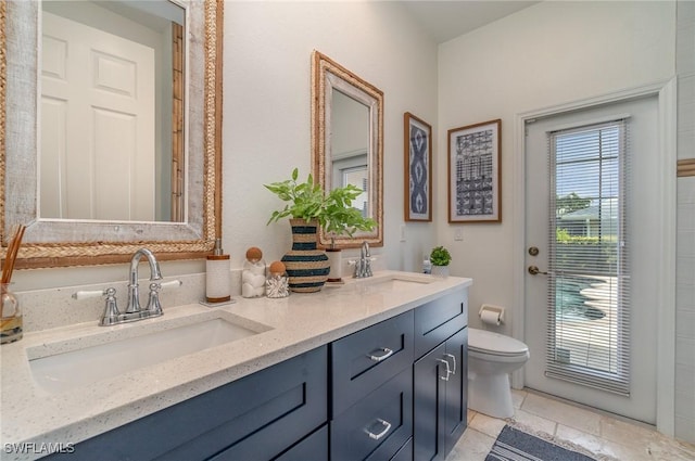 bathroom featuring toilet, double vanity, and a sink