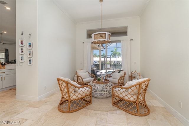 sitting room featuring stone finish flooring, ornamental molding, and baseboards