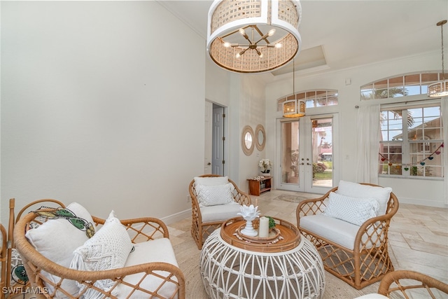 sitting room with an inviting chandelier, baseboards, ornamental molding, and stone tile flooring