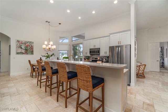 kitchen with a kitchen island, white cabinets, an inviting chandelier, appliances with stainless steel finishes, and tasteful backsplash