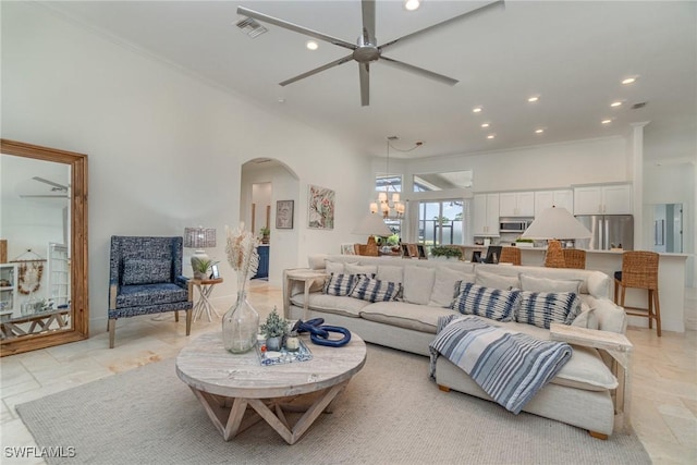 living area featuring arched walkways, recessed lighting, ceiling fan with notable chandelier, a towering ceiling, and visible vents