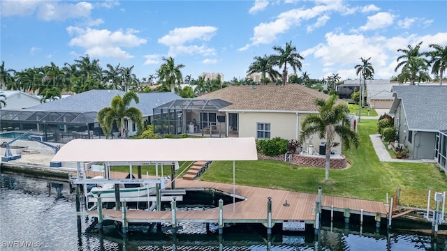 view of dock with glass enclosure, a water view, a lawn, and boat lift