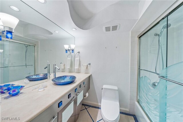 full bathroom featuring tile patterned flooring, bath / shower combo with glass door, toilet, and vanity