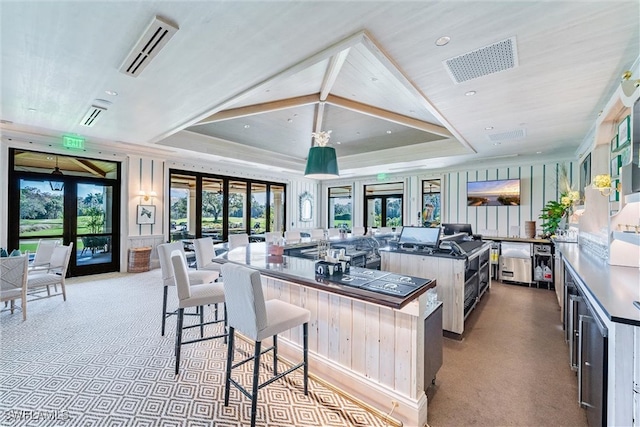 kitchen featuring a kitchen island, a breakfast bar, a raised ceiling, and light colored carpet