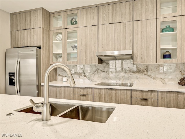 kitchen with black electric cooktop, light stone countertops, stainless steel fridge with ice dispenser, and range hood