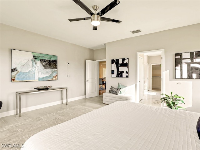 bedroom with ceiling fan, light hardwood / wood-style floors, and a walk in closet