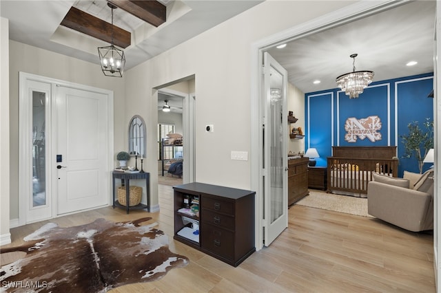 foyer entrance featuring ceiling fan with notable chandelier and light hardwood / wood-style floors