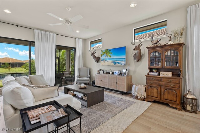 living room with light wood finished floors, a ceiling fan, and recessed lighting