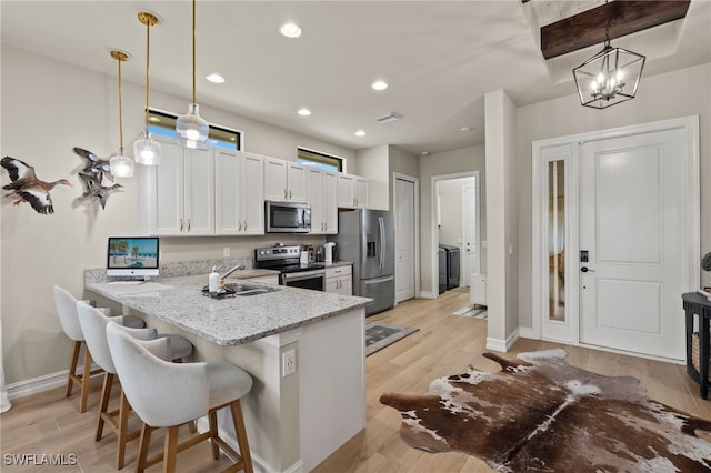 kitchen with a peninsula, white cabinets, stainless steel appliances, and decorative light fixtures